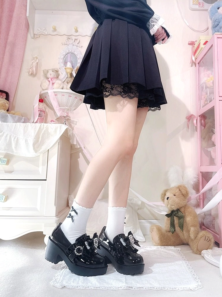 Back low angle view of black patent leather Jirai Kei loafers worn with pleated JK skirt and white crew socks in pastel pink bedroom aesthetic pastel bedroom styling