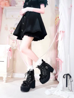 Black patent leather Jirai Kei platform ankle boots with heart-shaped pearl buckle, worn with black lolita dress and lace socks, side full-body fashion view