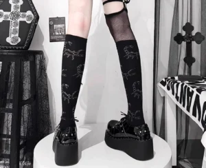 Black patent leather Jirai Kei platform shoes side view with fishnet knee-highs, metal cross ornament, thick platform sole with chain detail