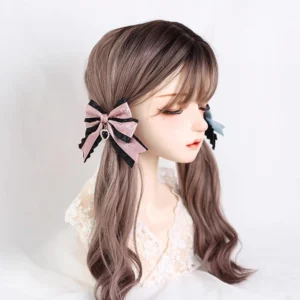 Jirai Kei black and pink bow hair clips with rhinestone heart charm and decorative ruffle trim styled on brown wavy twin-tail mannequin, three-quarter front view