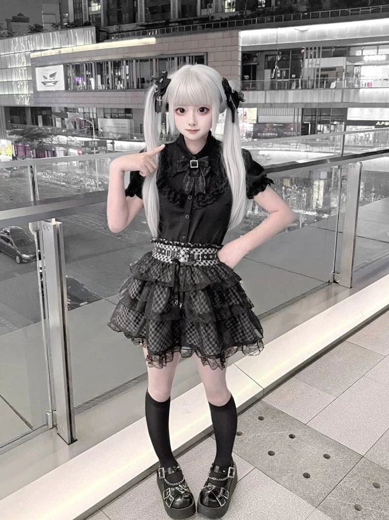 Jirai Kei black outfit three-quarter front view hand-on-hip pose studded waist belt details black and white plaid skirt layering