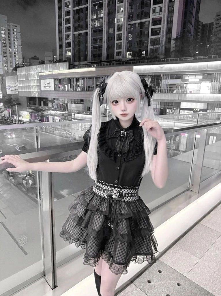 Jirai Kei black blouse and plaid skirt ensemble three-quarter front view model posing near collar detachable bow black stockings platform shoes
