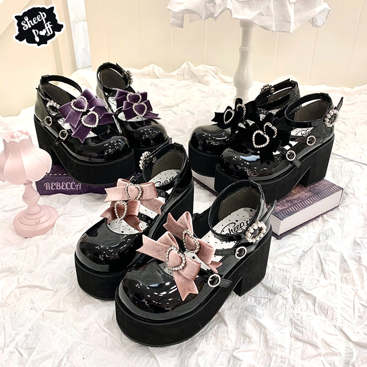 Flat lay overhead view of black patent leather platform shoes with two-tone butterfly bows and heart-shaped rhinestone buckles on decorative backdrop