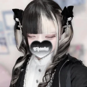 Split-dye twin tails goth girl model wearing black fluffy pompom hair ties with cross pendants on pigtails, paired with heart mesh face cover and dark aesthetic styling