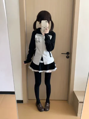 Black and white colorblock Jirai Kei outfit featuring black ruffled cake skirt with white lace trim, worn with black stockings and paired with matching hoodie on model with twin-tail hairstyle