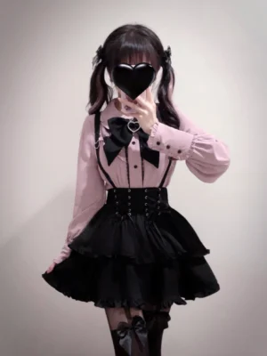 Close-up half-body front view of Jirai Kei suspender skirt with black corset waist, ruffled tiered layers, black bow tie detail and pink lacing