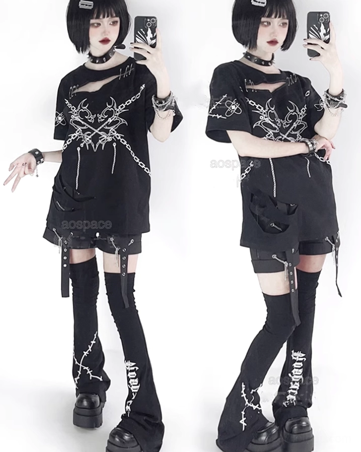 Flat lay studio display of black jirai kei punk clothing set including safety pin t-shirt with cross chain print and studded accessories