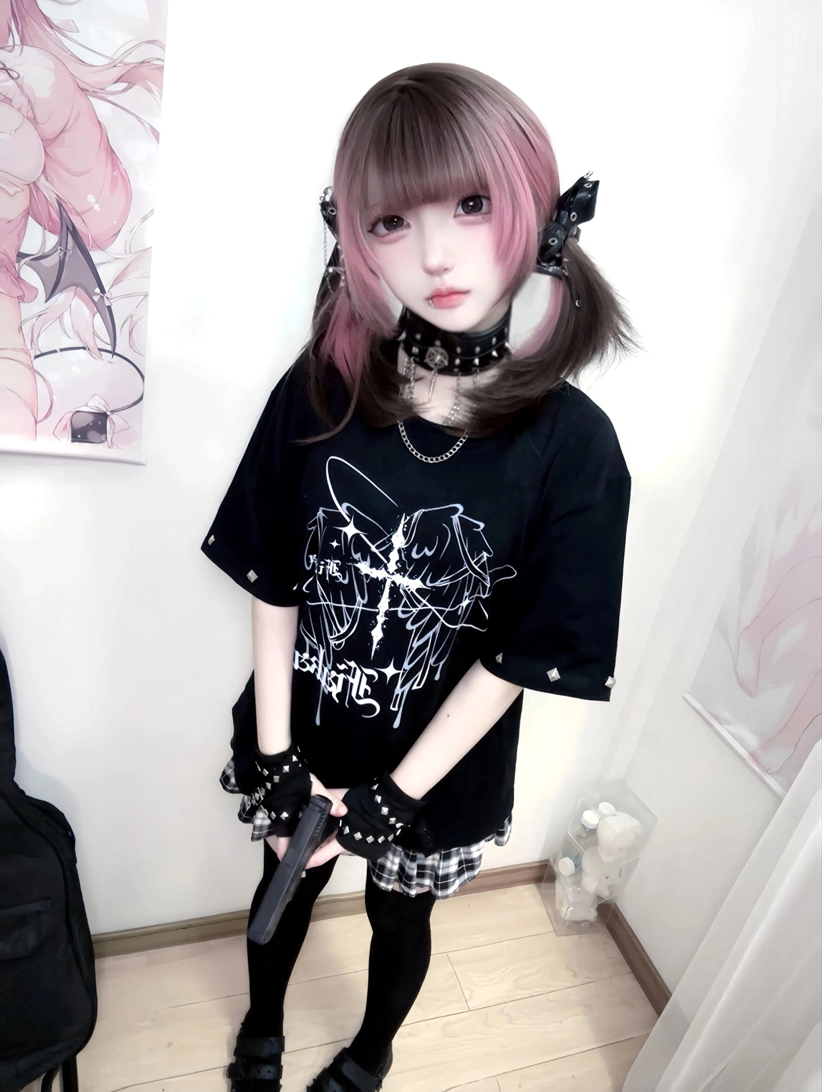 Front close-up shot of black oversized Jirai Kei t-shirt with white wing-cross graphic, model wearing layered chokers and celestial necklaces, holding dark prop demonstrating complete alternative fashion look