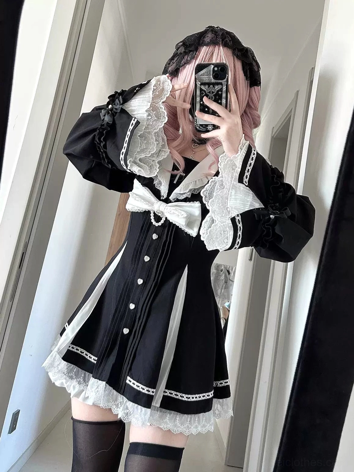 Jirai Kei black and white hime sleeve dress on pink-haired model in mirror selfie side-front view, showcasing ruffled long sleeves, white removable bow tie, and elegant silhouette