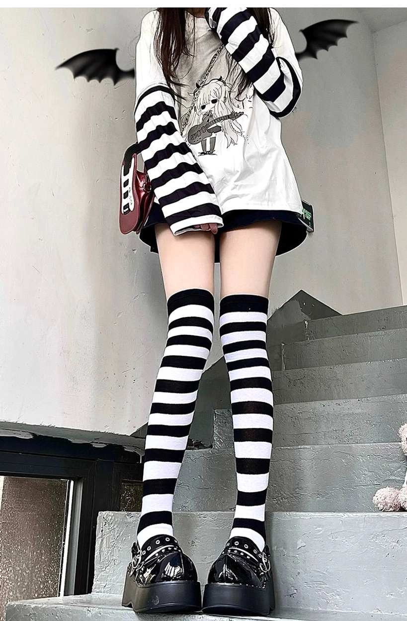 Black and white horizontal striped over-the-knee socks worn by female model with arm sleeves, indoor stair setting, Jirai Kei punk aesthetic