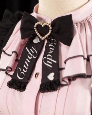 Close-up detail of Jirai Kei blouse collar showing heart pearl bow brooch candy printed ribbon layered ruffles