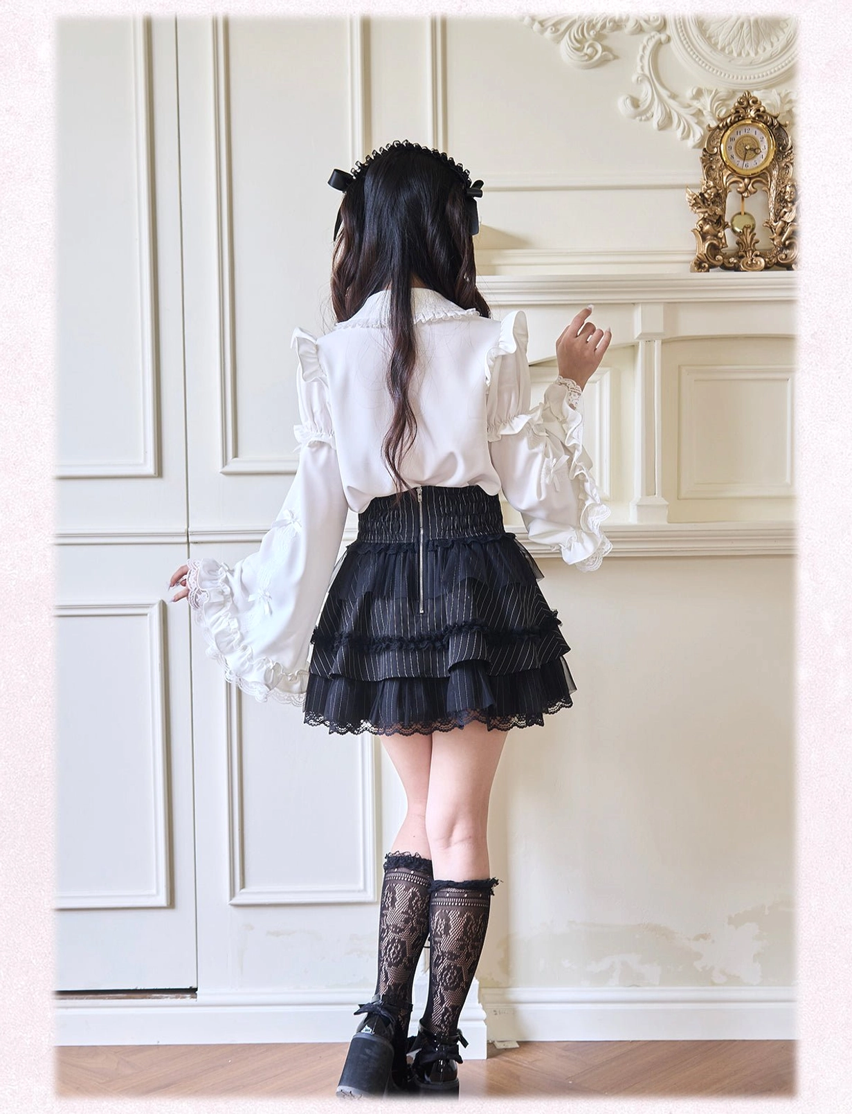 Back view of Jirai Kei blouse with long dramatic bell sleeves and black tiered ruffle skirt showcasing theatrical silhouette on vintage backdrop