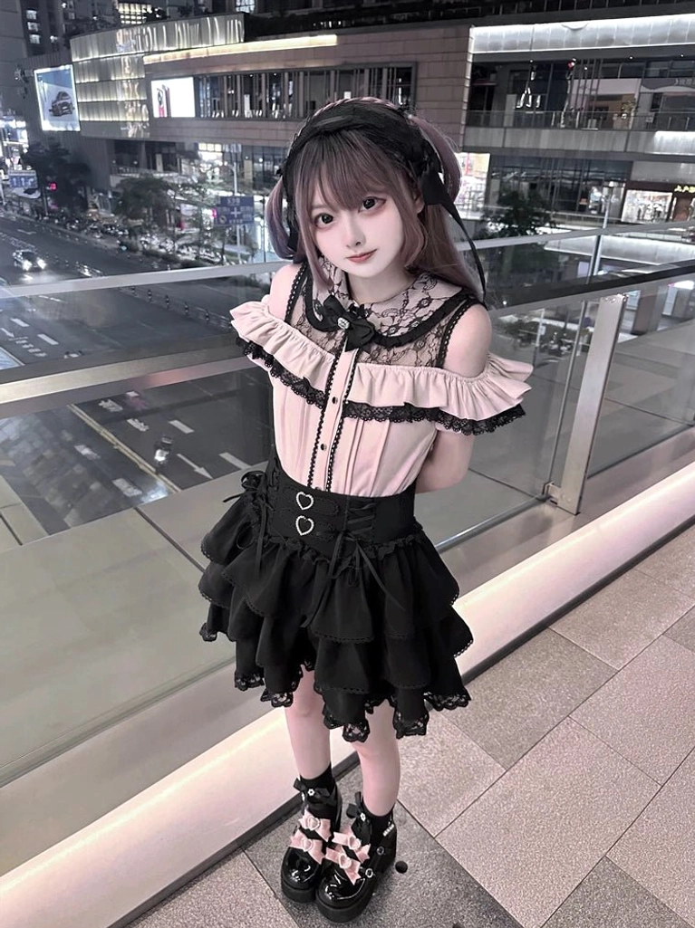 Full-body front view of Jirai Kei Gothic lolita ensemble showing double round waist buckles, front buttoned blouse design, and ruffled layered black skirt on young female model