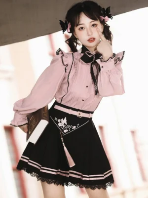 Jirai Kei fashion ensemble three-quarter side angle showing embroidered black bow tie, tassel pendant, and waist belt details on model with European street background