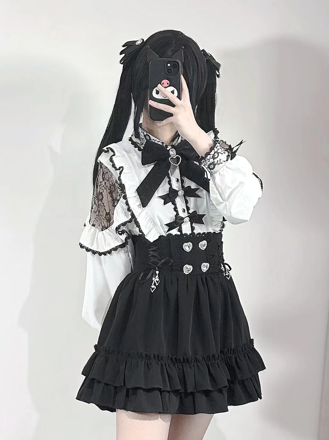 Gothic lolita two-piece outfit featuring white lace-accented blouse with star pendant bow tie, star chest decoration, and layered ruffled black skirt, studio display