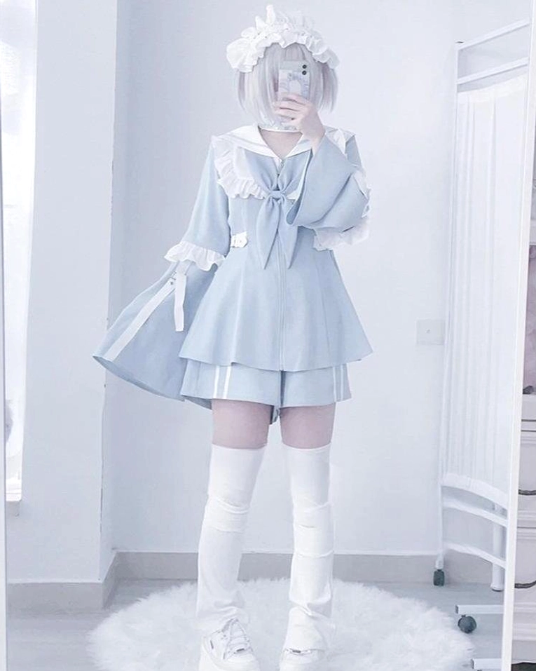 Front mirror selfie showing light blue sailor Jirai Kei two-piece set with ruffled collar, front bow, layered matching shorts, and white thigh highs in indoor mirror room