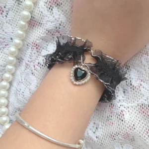 Jirai Kei black satin bow hair clip with silver heart charm and black gemstone on lace and pearl jewelry background