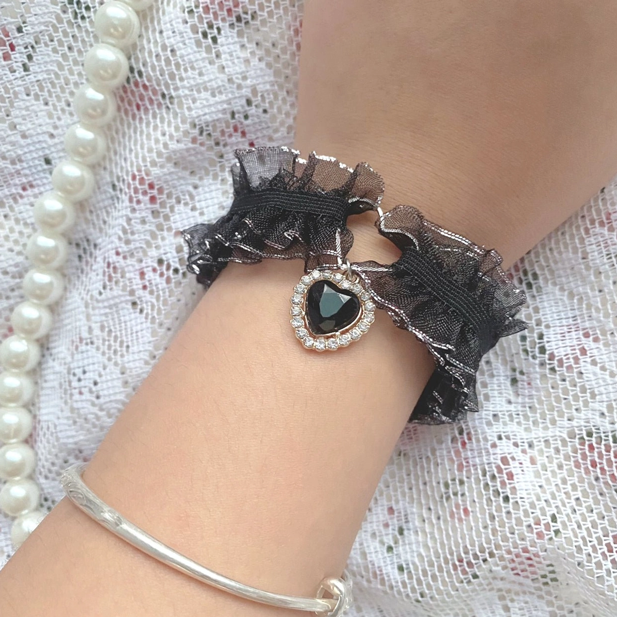 Jirai Kei black satin bow hair clip with silver heart charm and black gemstone on lace and pearl jewelry background