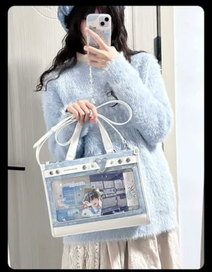 Blue and white boxy jirai kei ita bag with clear display window and detachable metal chain, front view worn with fuzzy sweater indoor