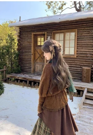 Back three-quarter full-body view of Jirai Kei brown sweater and plaid skirt ensemble with green scarf and decorative hair accessory against snowy cabin backdrop