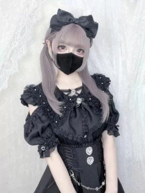 Gothic black Jirai Kei blouse with bunny ear collar and ruffled sleeves on model with hair bow