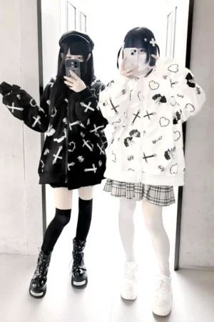 Jirai Kei bunny ear hoodie coat worn by two goth girls in mirror selfie, showcasing oversized fit with cross and heart anime prints and lace-trimmed bunny ear hood