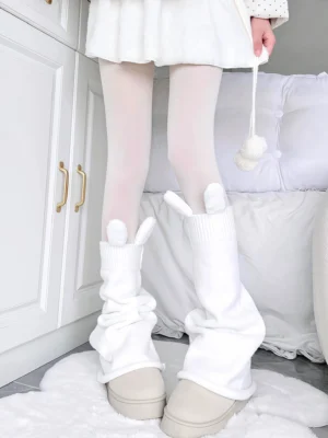 White bunny ear slouchy leg warmers with knitted texture paired with white opaque tights on female model wearing beige platform shoes in minimalist bedroom setting Jirai Kei aesthetic