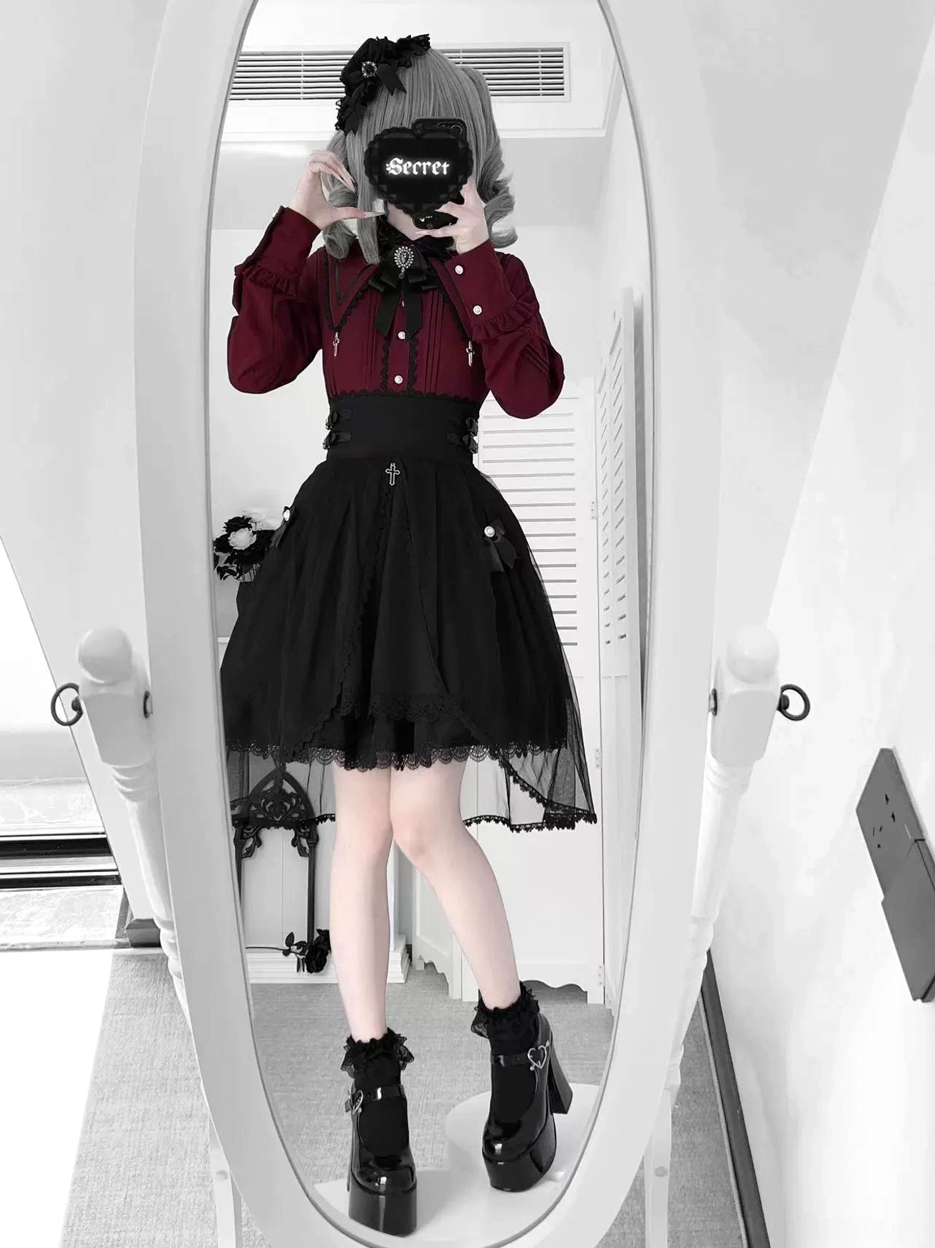 Jirai Kei outfit worn by model with twin-tail styled hair featuring burgundy blouse with cross brooch and black tulle skirt with decorative waist elements, full-body alternative color version