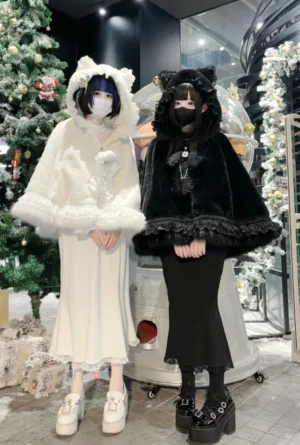 Two models wearing cat ear fleece cape hoodies in black and white, front view display of jirai kei winter coat styles with ruffle trim and fuzzy fabric