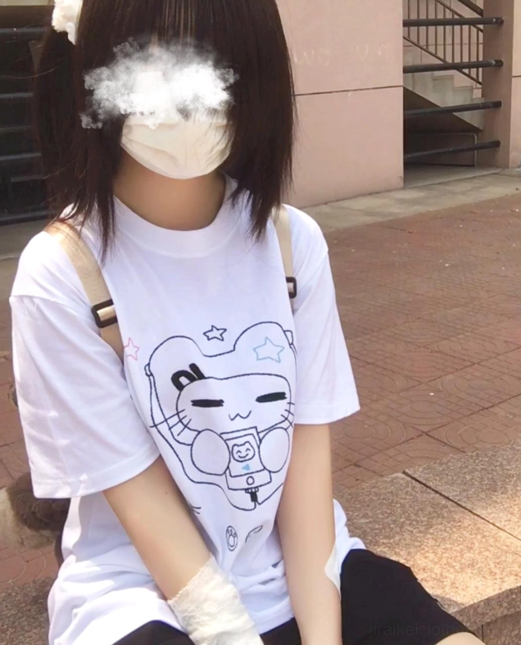 Close-up of model in navy Jirai Kei cat headset T-shirt with pink choker looking downward in white interior room setting