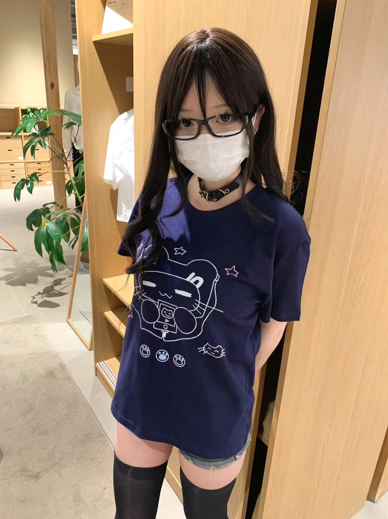 Side profile of model in navy Jirai Kei cat headset T-shirt paired with denim shorts and thigh-high socks in clothing store interior