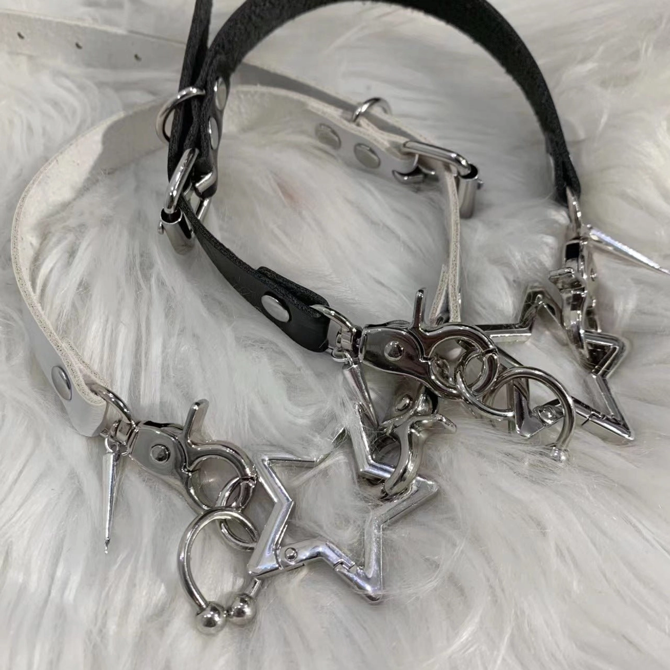 White and black PU leather Jirai Kei choker set with hollow star and spike metal charms on white faux fur background