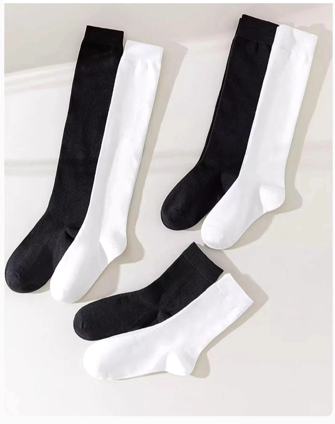 Flat lay collection showing classic solid color compression socks in black and white with multiple length options from crew to over-the-knee styles