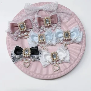 Dusty pink Jirai Kei bow hair clips pair with pearl heart pendant and rhinestone accents on embossed ceramic plate, flat lay showcase