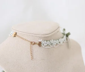 Green Jirai Kei vintage-inspired choker necklace side profile with white lace trim, adjustable gold chain extender, and small ribbon bow detail on fabric neck display—elegant alternative jewelry styling