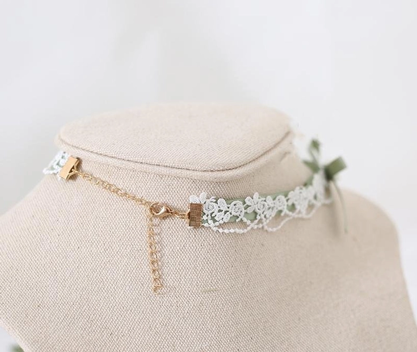 Green Jirai Kei vintage-inspired choker necklace side profile with white lace trim, adjustable gold chain extender, and small ribbon bow detail on fabric neck display—elegant alternative jewelry styling