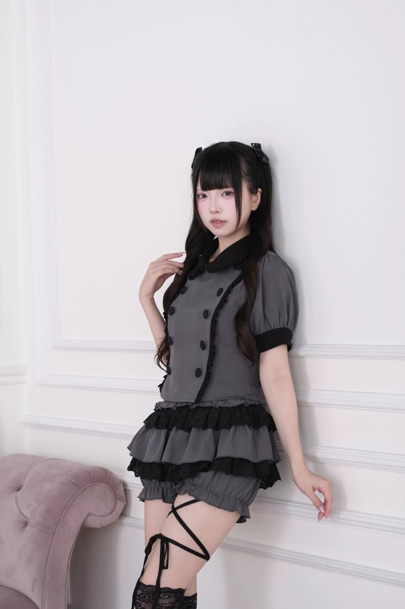 Close-up partial front view of grey jirai kei blouse ruffles and tiered skort with crisscross thigh strap details on white studio background