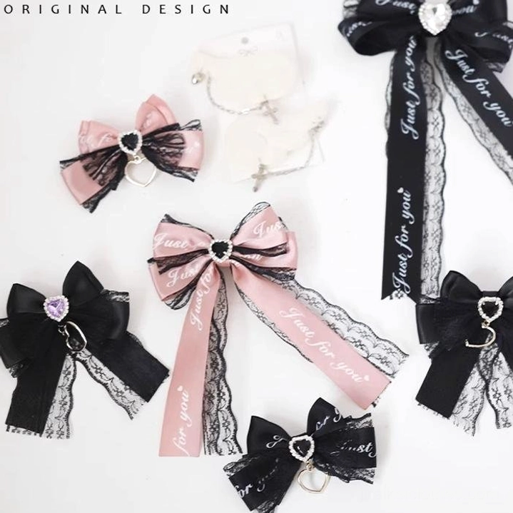 Assorted Jirai Kei hair accessories collection showing black and pink bows with lace trim, printed ribbons, and crystal heart charms, flat lay top-down view
