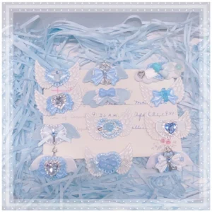 Assorted jirai kei hair clips collection flat lay with blue shredded paper display featuring devil wings heart crosses and rhinestone decorations