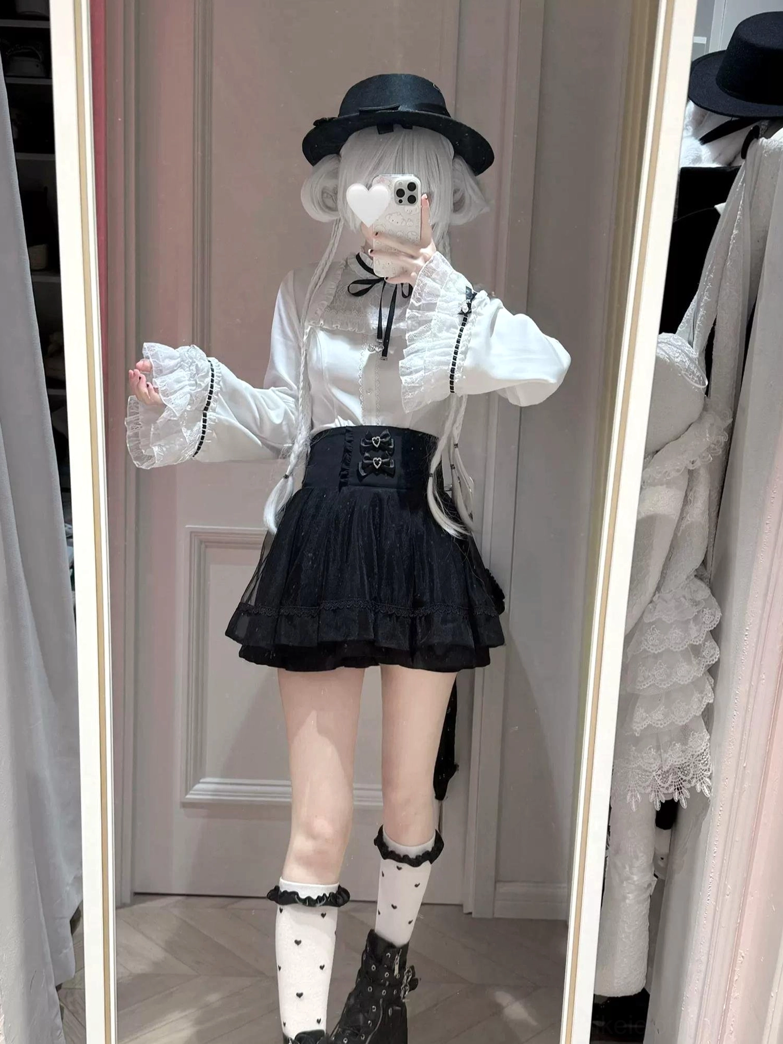 Full-body front mirror selfie of jirai kei heart-buckle blouse and high-waisted a-line skirt with double rhinestone bows, styled with black combat boots and lace-trimmed knee-high socks