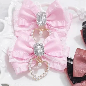 Light pink Jirai Kei heart pearl hair clip with lace bow and rhinestone charm flat lay on white lace serving tray showing delicate design details