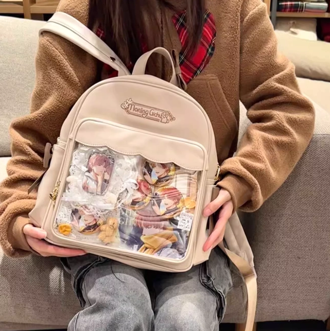 Kawaii anime merchandise itabag beige color held by girl in brown coat indoor sofa setting