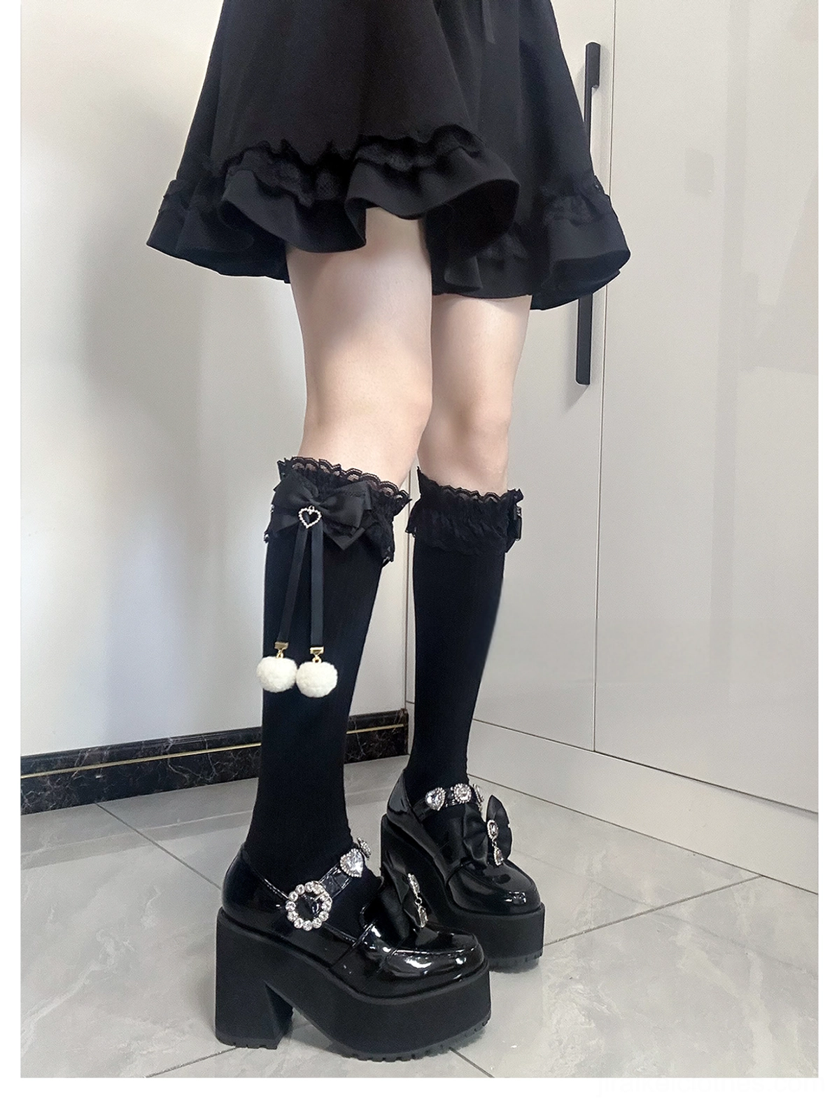 Jirai Kei knee-high socks direct front full leg view one sock with black bow and white pom-pom another with only lace cuff all-black fabric platform leather shoes
