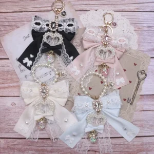 Jirai Kei lace bow keychain and bag charm collection in four color variants displayed on wooden desktop with vintage lace and decorative props