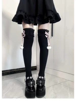 Jirai Kei lace bow pom-pom thigh-high socks front view black fabric with pink bow and white pom-pom detail worn with black ruffled mini skirt and platform leather shoes