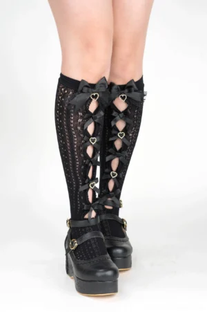Black mid-calf Jirai Kei socks front full leg view featuring black ribbon bows heart-shaped rhinestone decorations with platform shoes