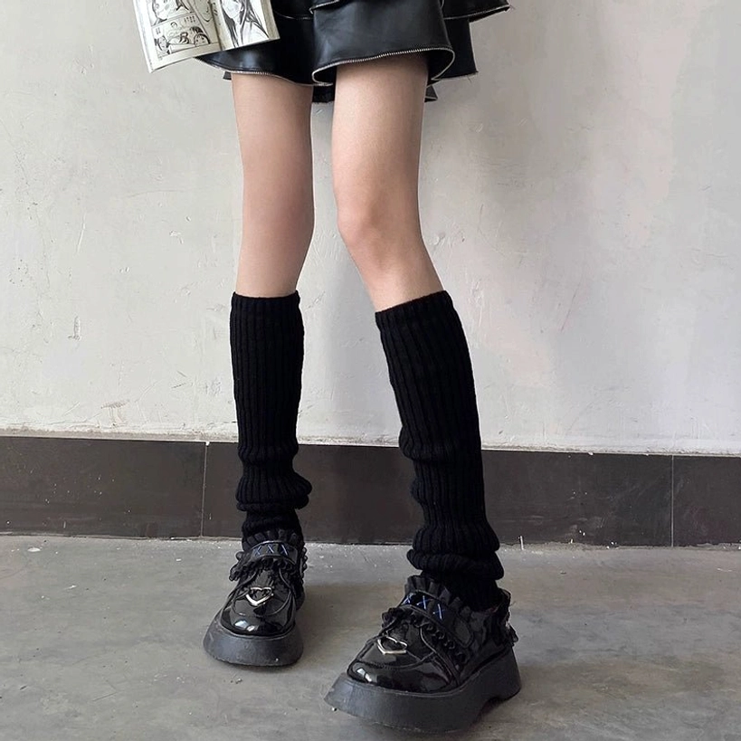 Pure black thick vertical rib knit jirai kei leg warmer mid-calf style with leather mini skirt and platform loafers indoor wall backdrop