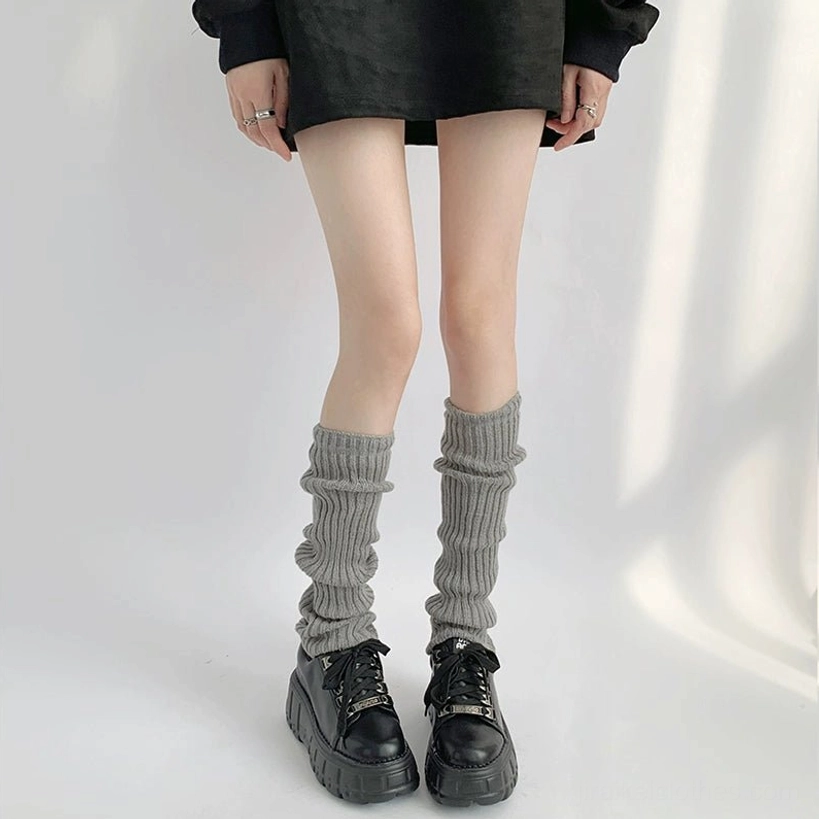 Light grey loose ribbed stacked jirai kei leg warmer mid-calf length with black mini skirt and platform sneakers indoor plain background