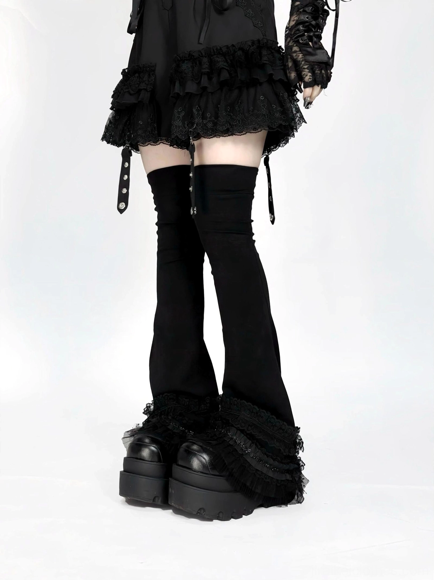 Black jirai kei over-the-knee leg warmers with white lace ruffled cuffs, low front view showcasing flared silhouette and anti-slip band