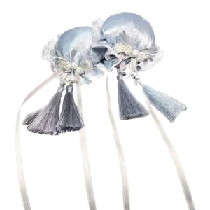 Light blue satin Jirai Kei hair bun clips with lace trim and tassel decorations, overhead flat lay product photography, Chinese-inspired hair accessory with embroidered details